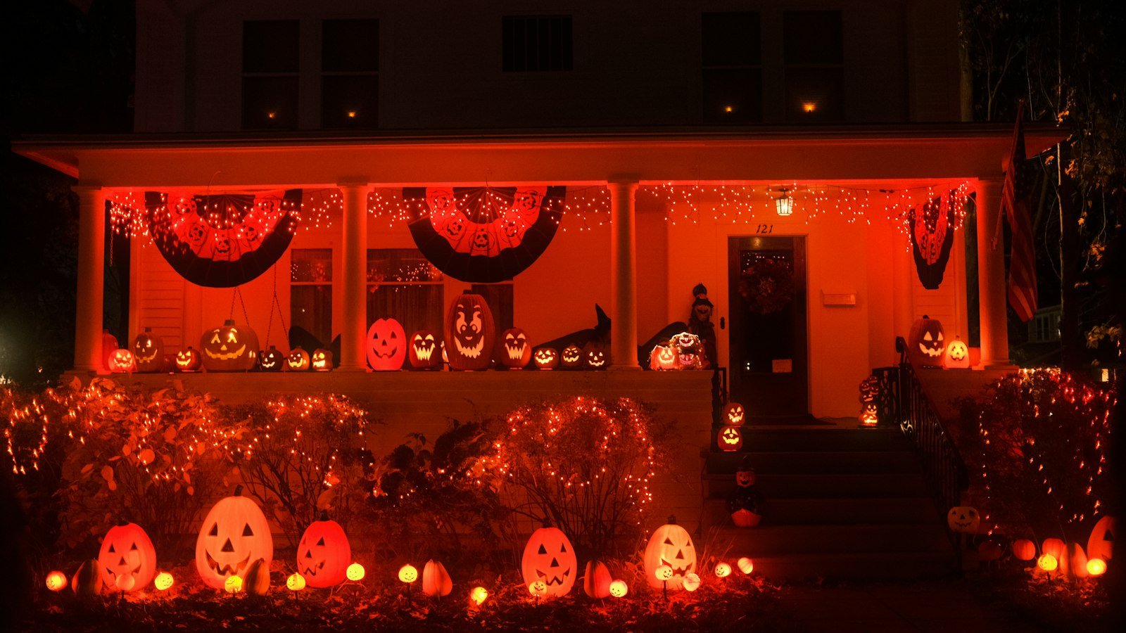 A house decorated for Halloween with pumpkins and orange lights at dusk