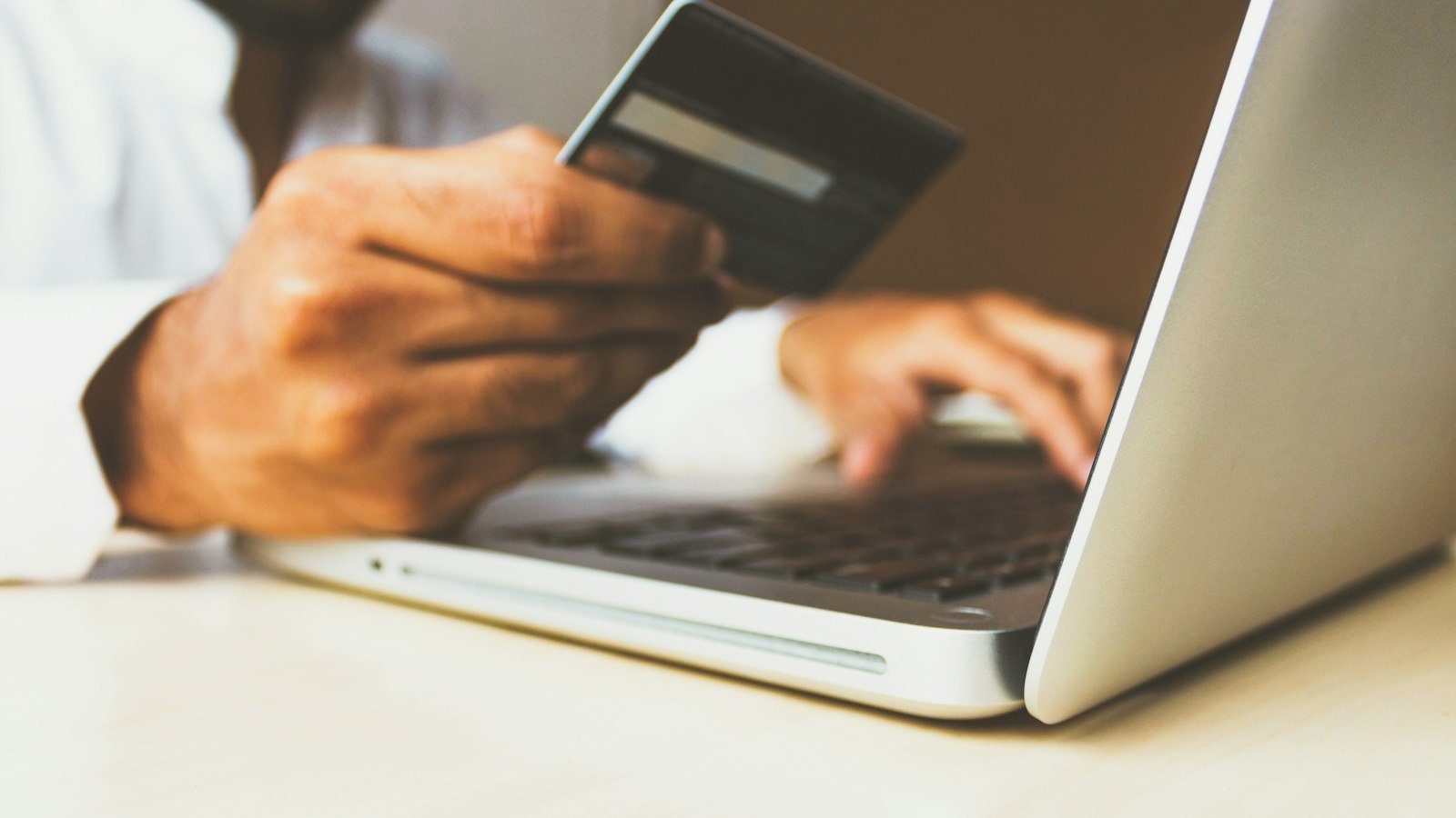 Person using a laptop while holding a credit card for an online purchase