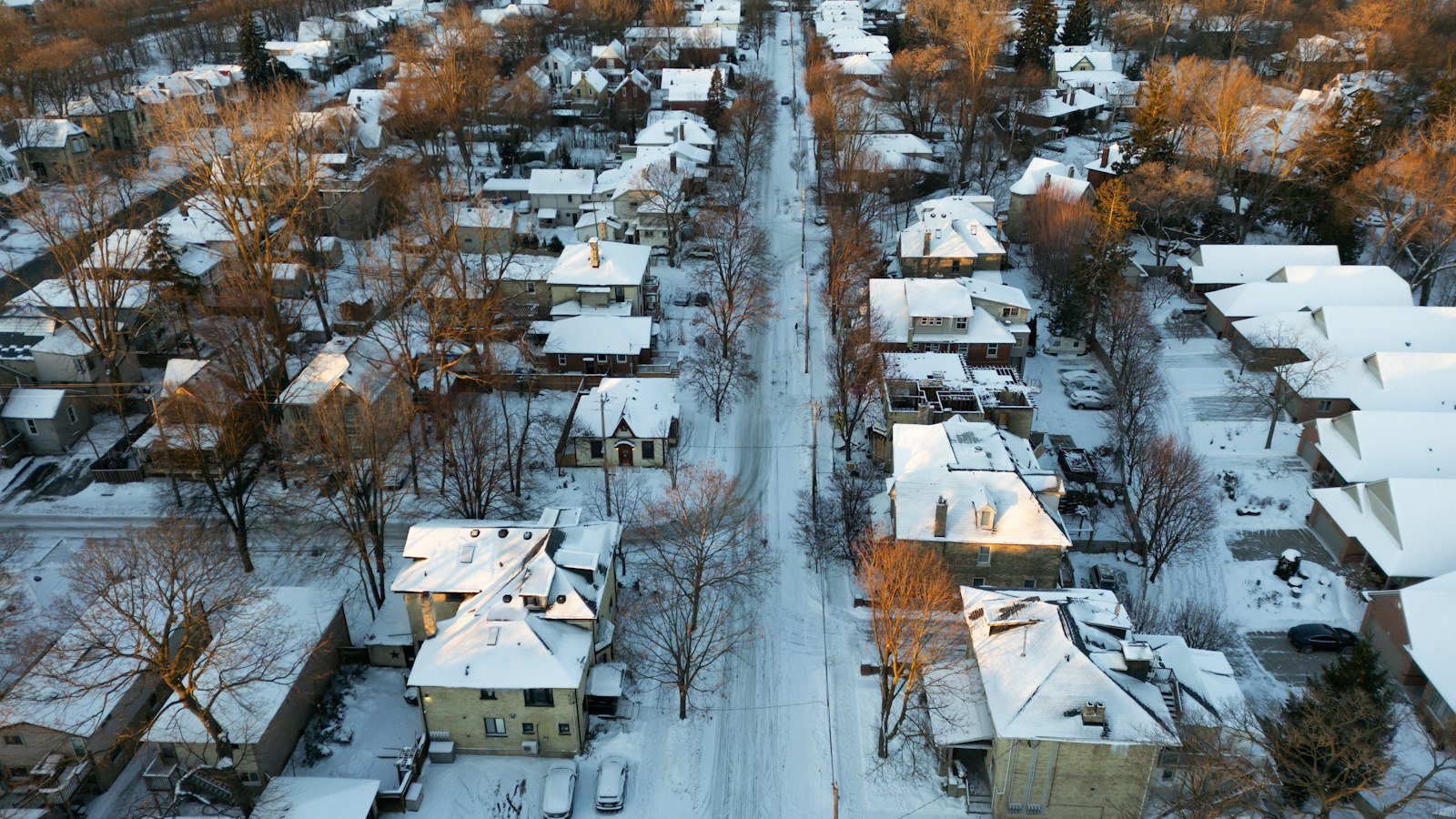 Aerial view of a snow-covered neighborhood street at sunrise