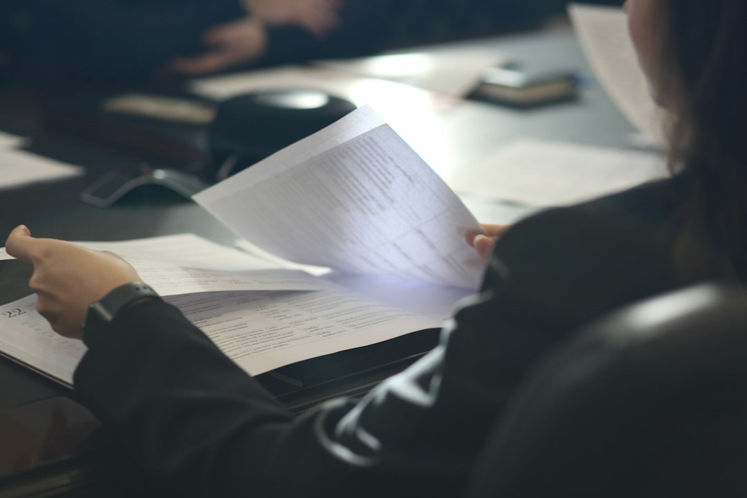 Woman sitting at a table carefully reading a paper document