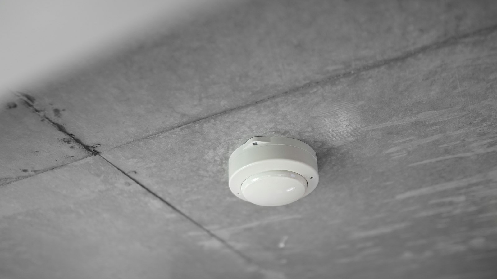 A white smoke alarm mounted on a ceiling