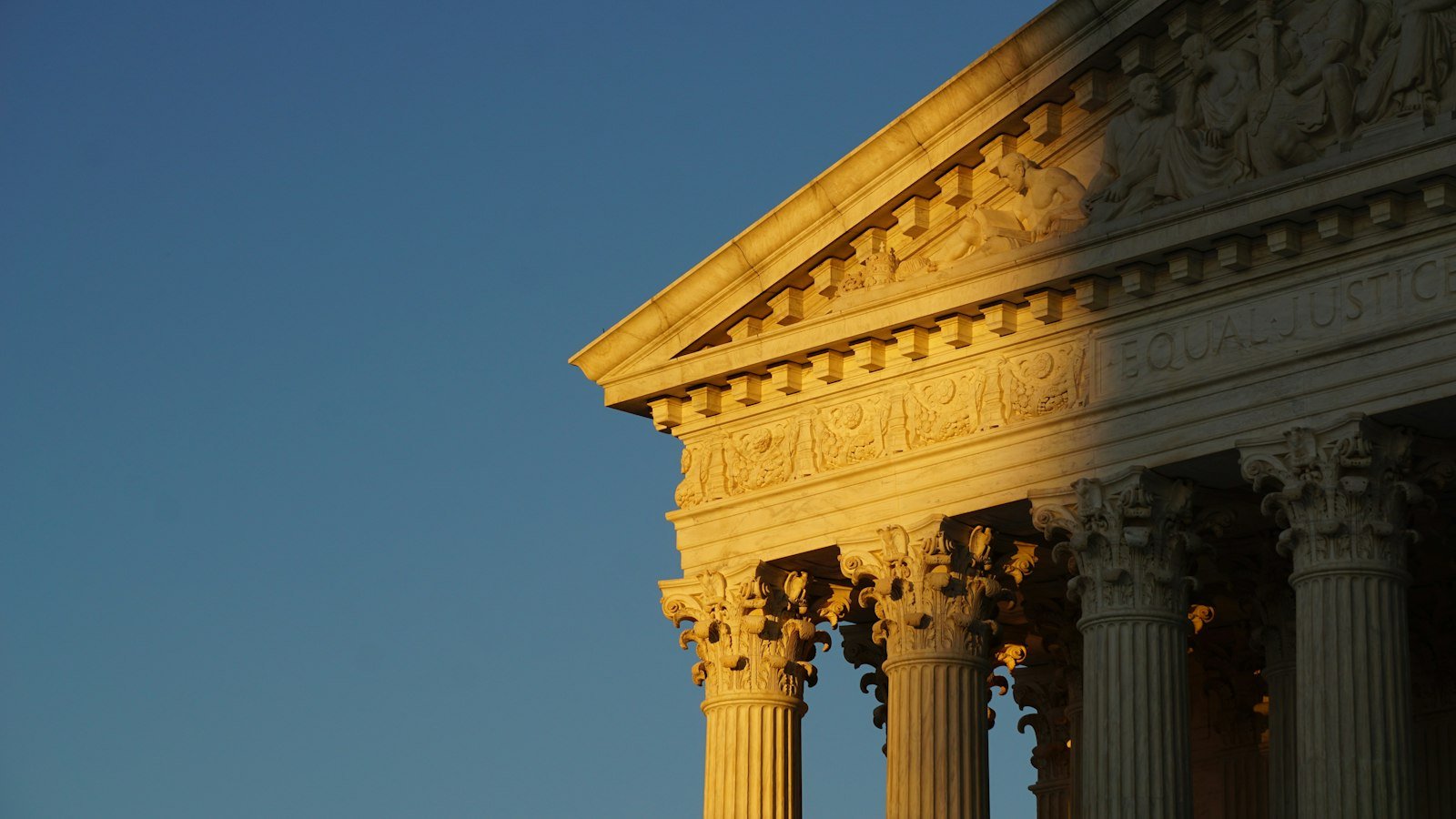 The front facade of the Supreme Court of the United States in Washington, DC under a blue sky